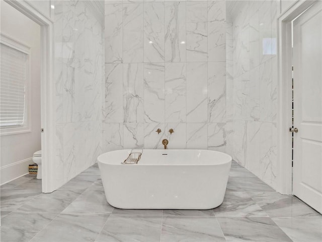 bathroom featuring tile walls, a tub to relax in, and toilet