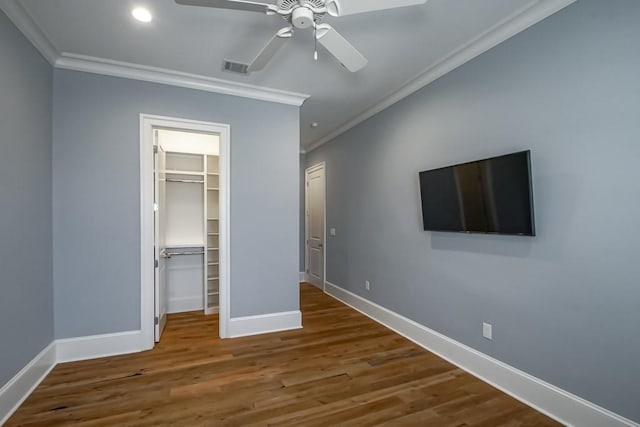 unfurnished bedroom featuring ceiling fan, crown molding, hardwood / wood-style flooring, a spacious closet, and a closet