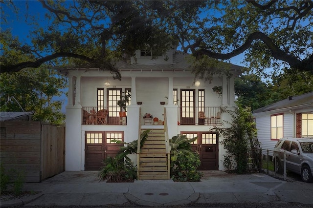 view of front facade featuring french doors, covered porch, and a garage