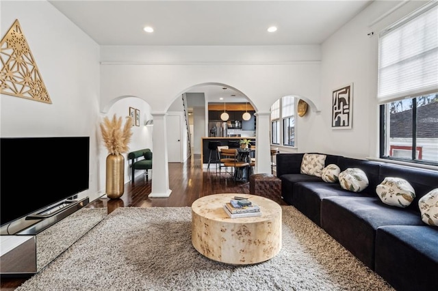 living room with dark wood-type flooring and decorative columns