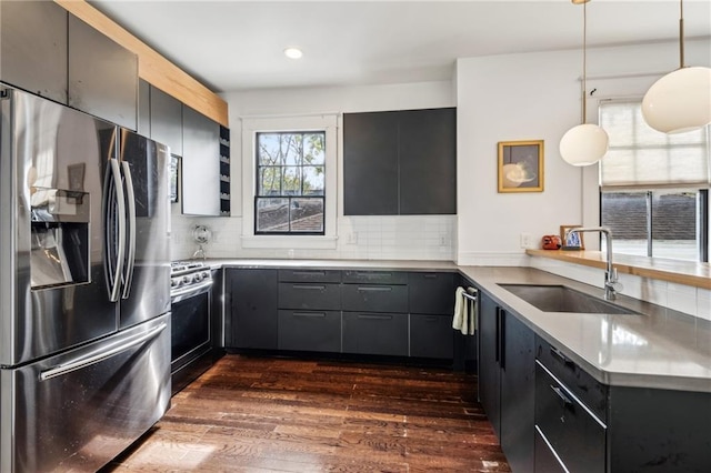 kitchen with appliances with stainless steel finishes, backsplash, dark wood-type flooring, hanging light fixtures, and sink