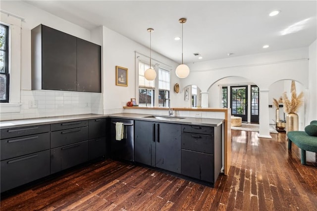 kitchen featuring pendant lighting, dishwasher, a healthy amount of sunlight, decorative backsplash, and sink