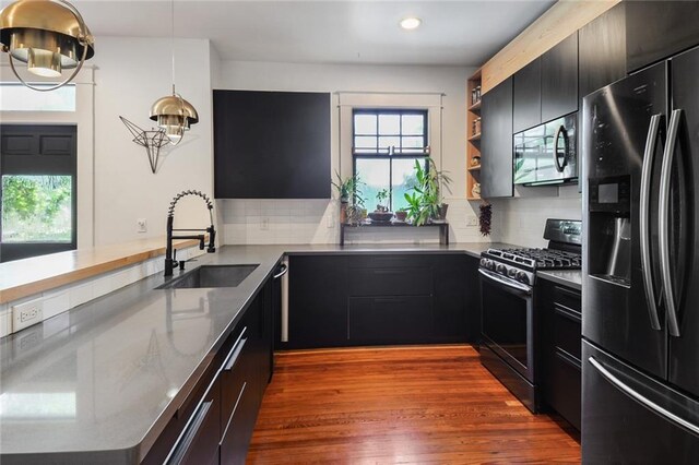 kitchen featuring stainless steel appliances, kitchen peninsula, hanging light fixtures, and sink