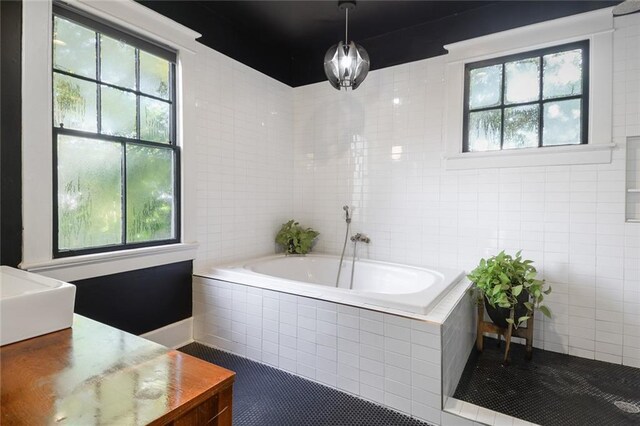 bathroom featuring a healthy amount of sunlight, tile patterned flooring, and tiled tub