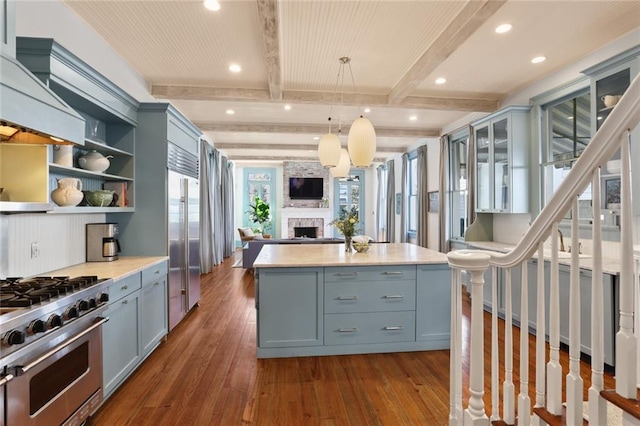 kitchen featuring a kitchen island, decorative light fixtures, a fireplace, plenty of natural light, and beam ceiling