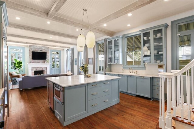 kitchen featuring a center island, decorative light fixtures, dark wood-type flooring, sink, and beam ceiling