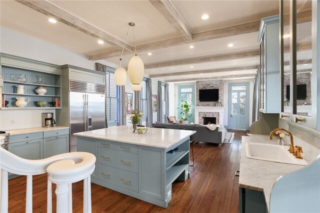 kitchen with built in fridge, beam ceiling, hanging light fixtures, and a center island