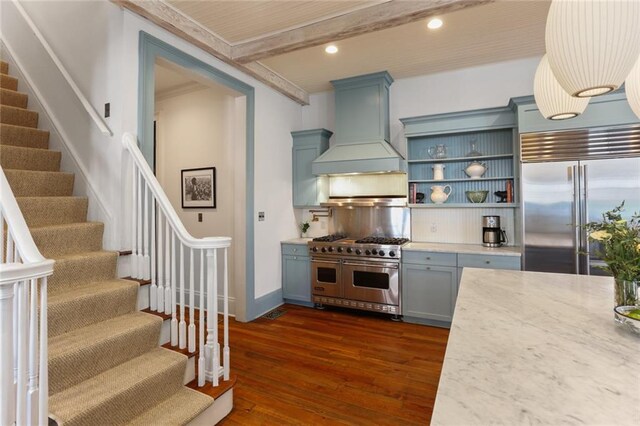 kitchen featuring premium appliances, dark wood-type flooring, beamed ceiling, light stone counters, and custom range hood