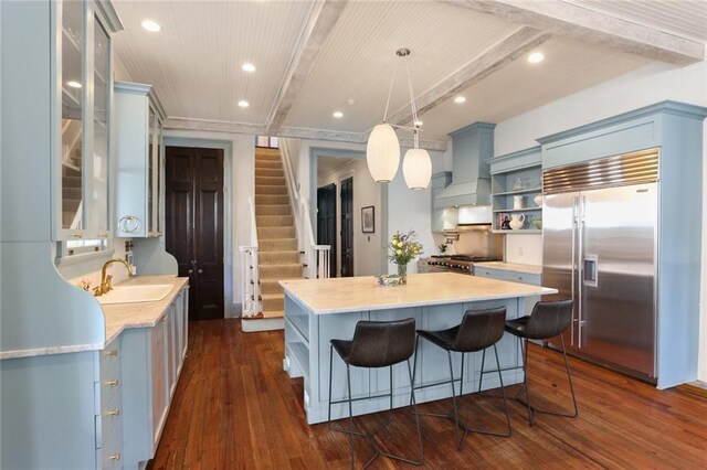 kitchen with custom exhaust hood, premium appliances, beamed ceiling, a center island, and sink