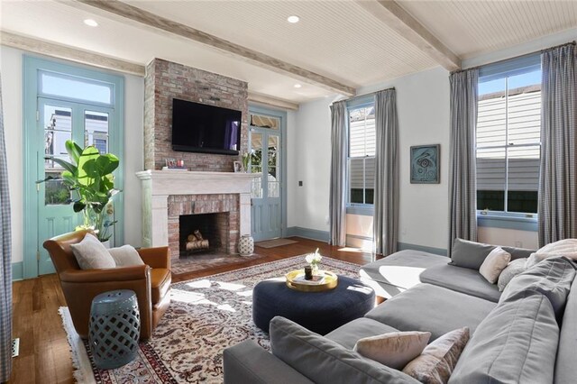 living room featuring a fireplace, beamed ceiling, and hardwood / wood-style flooring