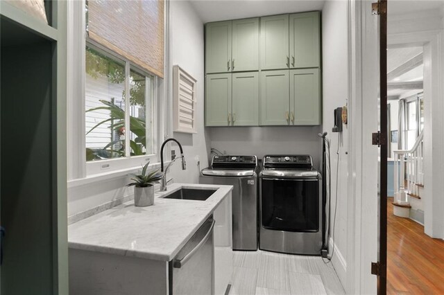 laundry room with cabinets, independent washer and dryer, and sink