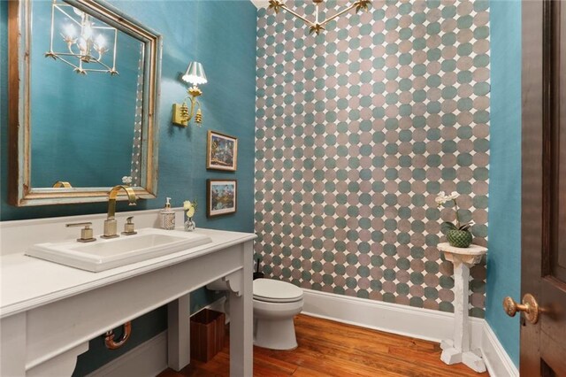 bathroom with toilet, a chandelier, hardwood / wood-style flooring, and sink