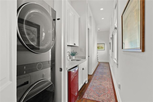 laundry area with stacked washing maching and dryer, dark wood-type flooring, and sink