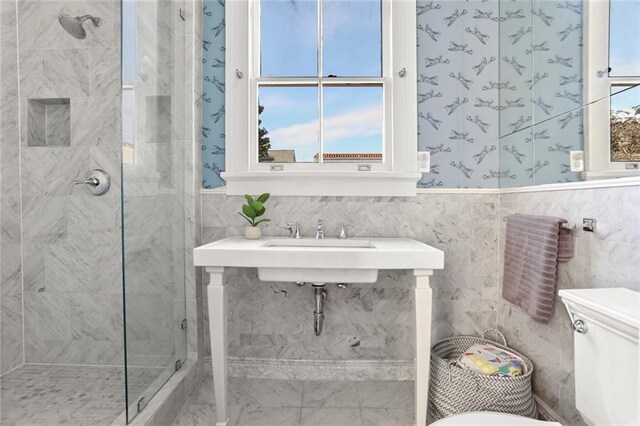 bathroom featuring a wealth of natural light, toilet, and a tile shower