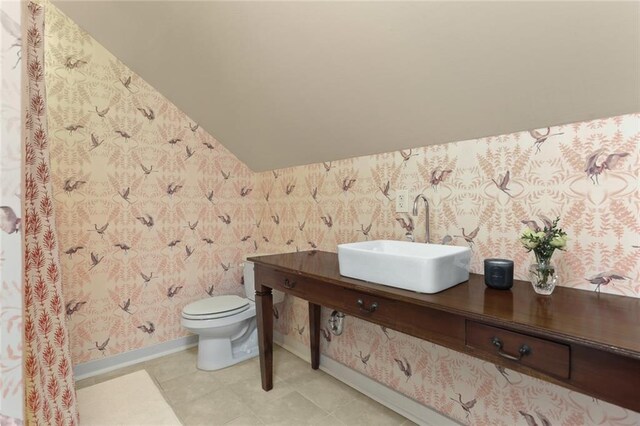 bathroom with toilet, lofted ceiling, and sink