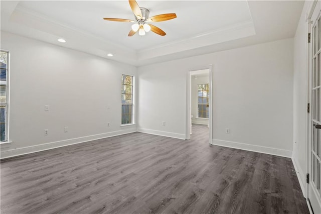 spare room featuring a raised ceiling, crown molding, dark wood-type flooring, and ceiling fan