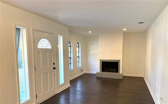 foyer entrance featuring a fireplace, plenty of natural light, and dark hardwood / wood-style floors