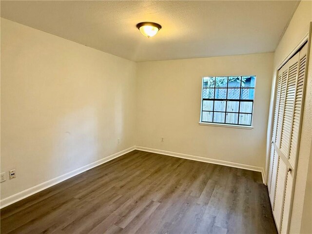 unfurnished bedroom with a closet and dark wood-type flooring