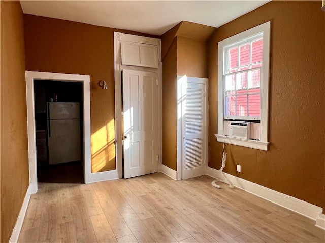 unfurnished bedroom with white fridge and light wood-type flooring