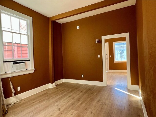 spare room featuring light wood-type flooring, cooling unit, and plenty of natural light