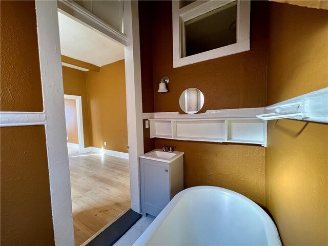 bathroom with vanity, wood-type flooring, and a bath