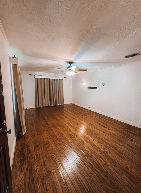 unfurnished room with ceiling fan, a textured ceiling, and dark hardwood / wood-style floors