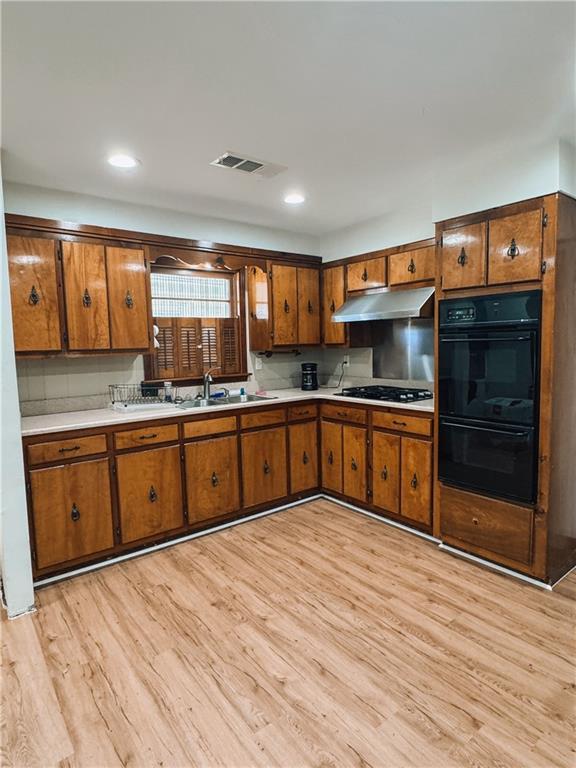 kitchen featuring backsplash, gas cooktop, sink, light hardwood / wood-style flooring, and black double oven