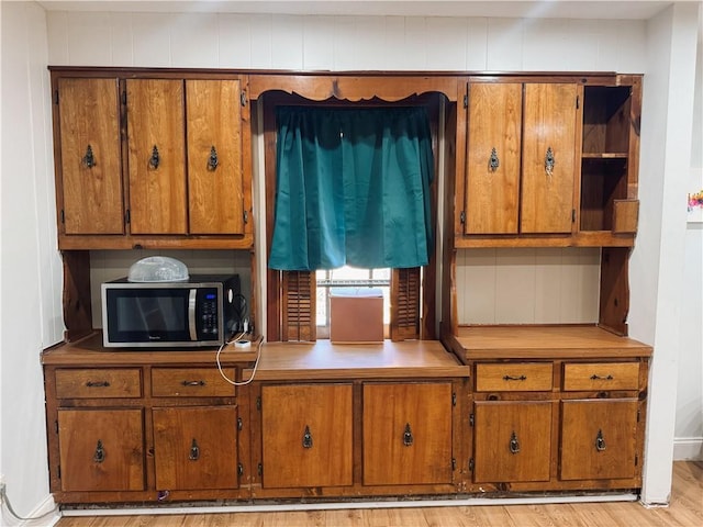 kitchen with light wood-type flooring and wooden walls