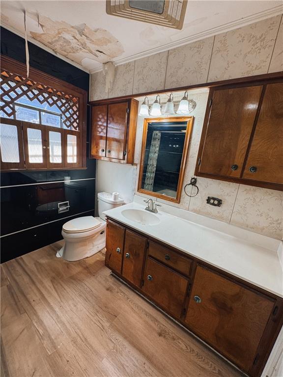 bathroom featuring toilet, crown molding, hardwood / wood-style flooring, and vanity