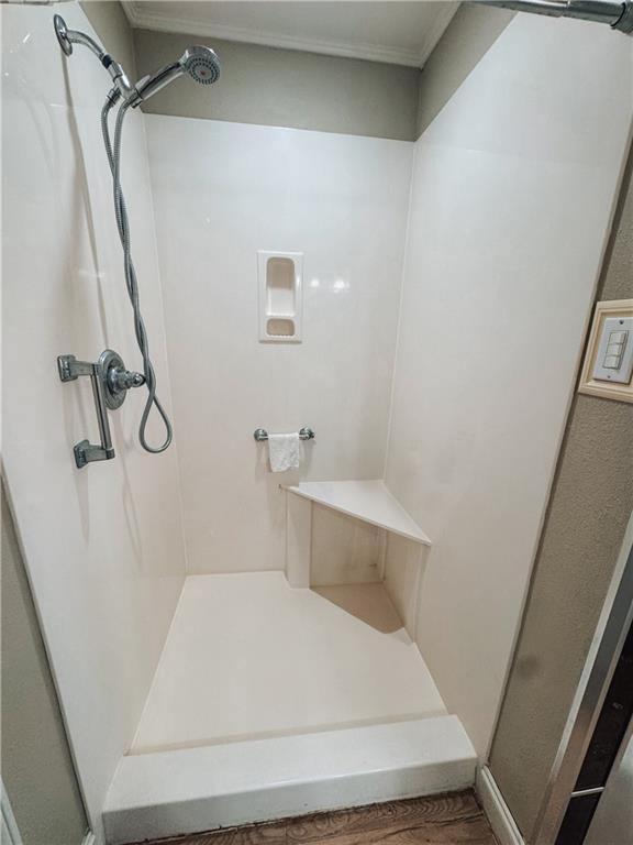 bathroom featuring ornamental molding, hardwood / wood-style flooring, and walk in shower