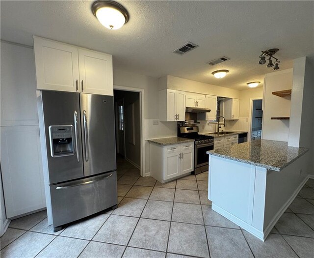 kitchen featuring white cabinetry, kitchen peninsula, stainless steel appliances, light tile patterned flooring, and stone counters