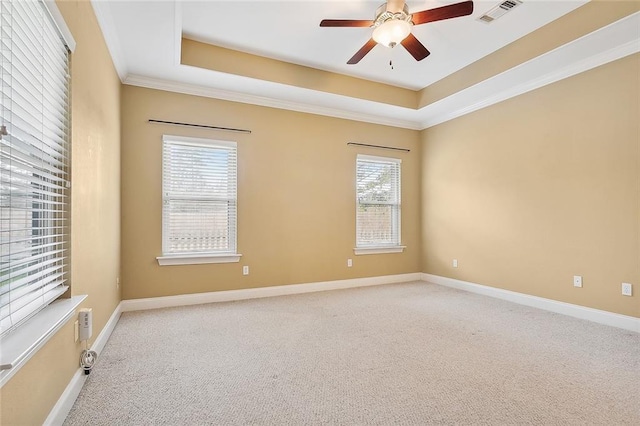 carpeted empty room featuring a raised ceiling, ceiling fan, and crown molding