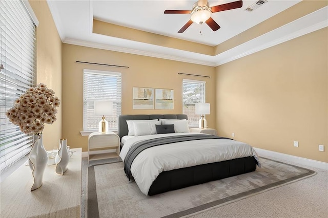 bedroom featuring a raised ceiling, ceiling fan, crown molding, and carpet floors