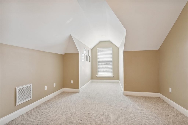 additional living space with light colored carpet and vaulted ceiling