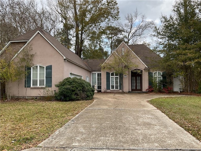 view of front of property featuring a front lawn, a garage, and french doors