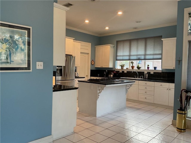 kitchen with appliances with stainless steel finishes, a kitchen island, white cabinets, a breakfast bar, and sink