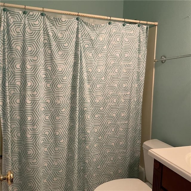 bathroom featuring toilet, vanity, and a shower