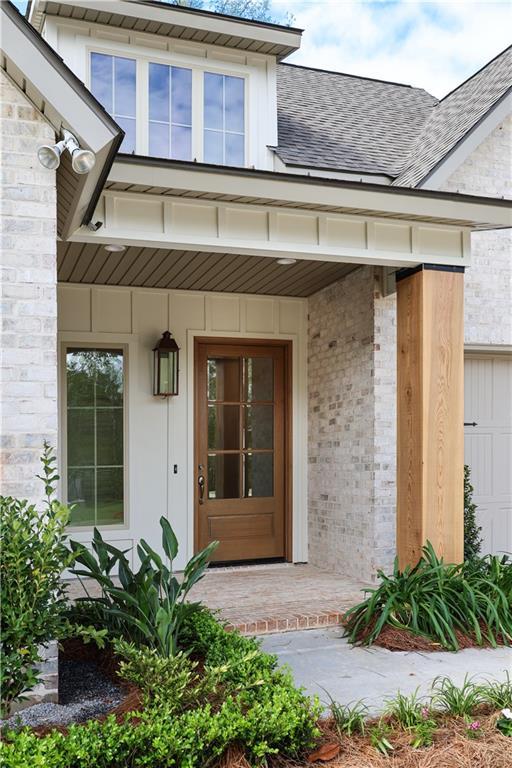 5044 Twin River Pl, Covington, LA 70433 - view of exterior entry featuring covered porch, a shingled roof, and brick siding