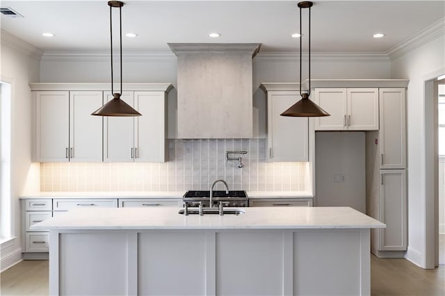5044 Twin River Pl, Covington, LA 70433 - kitchen featuring a sink, light wood finished floors, tasteful backsplash, a center island with sink, and light stone counters