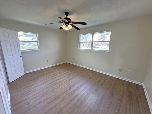 unfurnished room with a wealth of natural light, a textured ceiling, and light hardwood / wood-style flooring