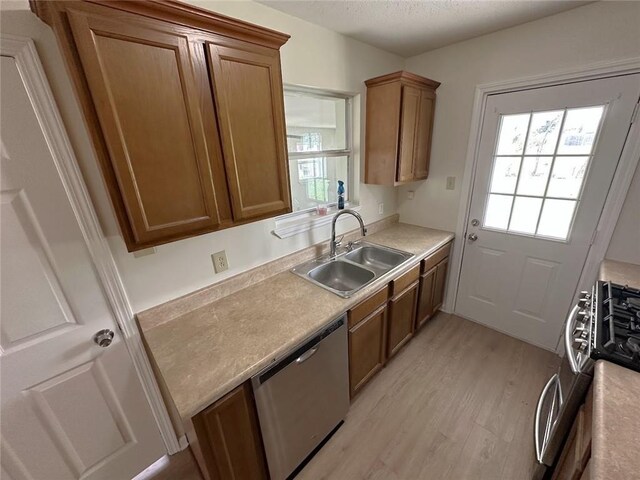 kitchen with sink, stainless steel appliances, and light hardwood / wood-style floors