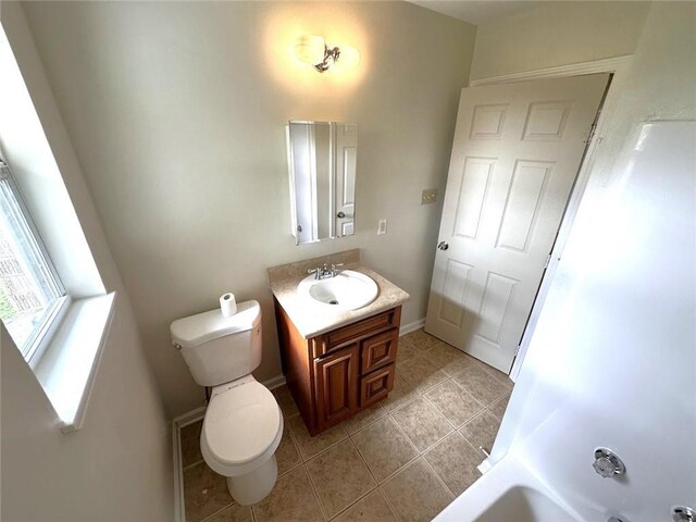 bathroom featuring toilet, vanity, tile patterned floors, and a bathing tub