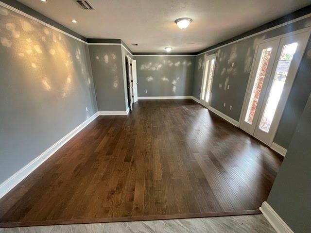 empty room featuring dark hardwood / wood-style floors, a wealth of natural light, and ornamental molding