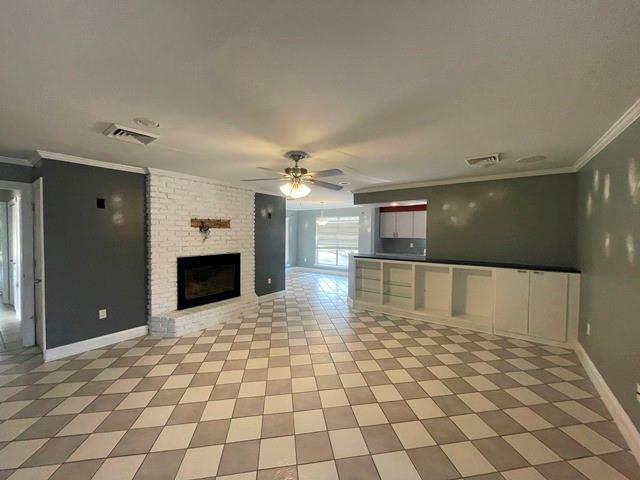 unfurnished living room featuring a fireplace, visible vents, and ornamental molding