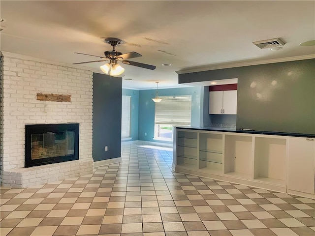 kitchen featuring visible vents, a ceiling fan, ornamental molding, a fireplace, and white cabinetry