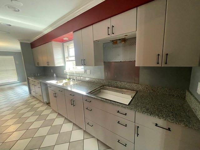 kitchen with a sink, white cabinets, ornamental molding, dishwasher, and stovetop