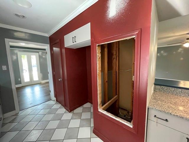 hall with french doors, light tile patterned flooring, crown molding, and baseboards