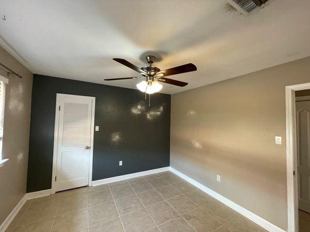 spare room with visible vents, ceiling fan, baseboards, and light tile patterned floors