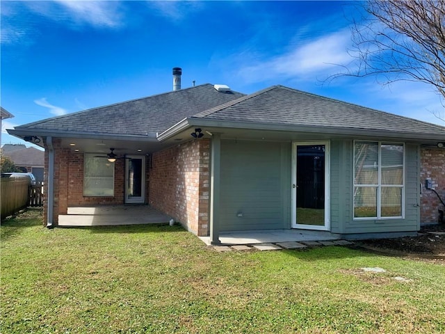 rear view of house with a patio, brick siding, roof with shingles, and a lawn