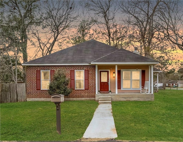 view of front of home with covered porch and a yard